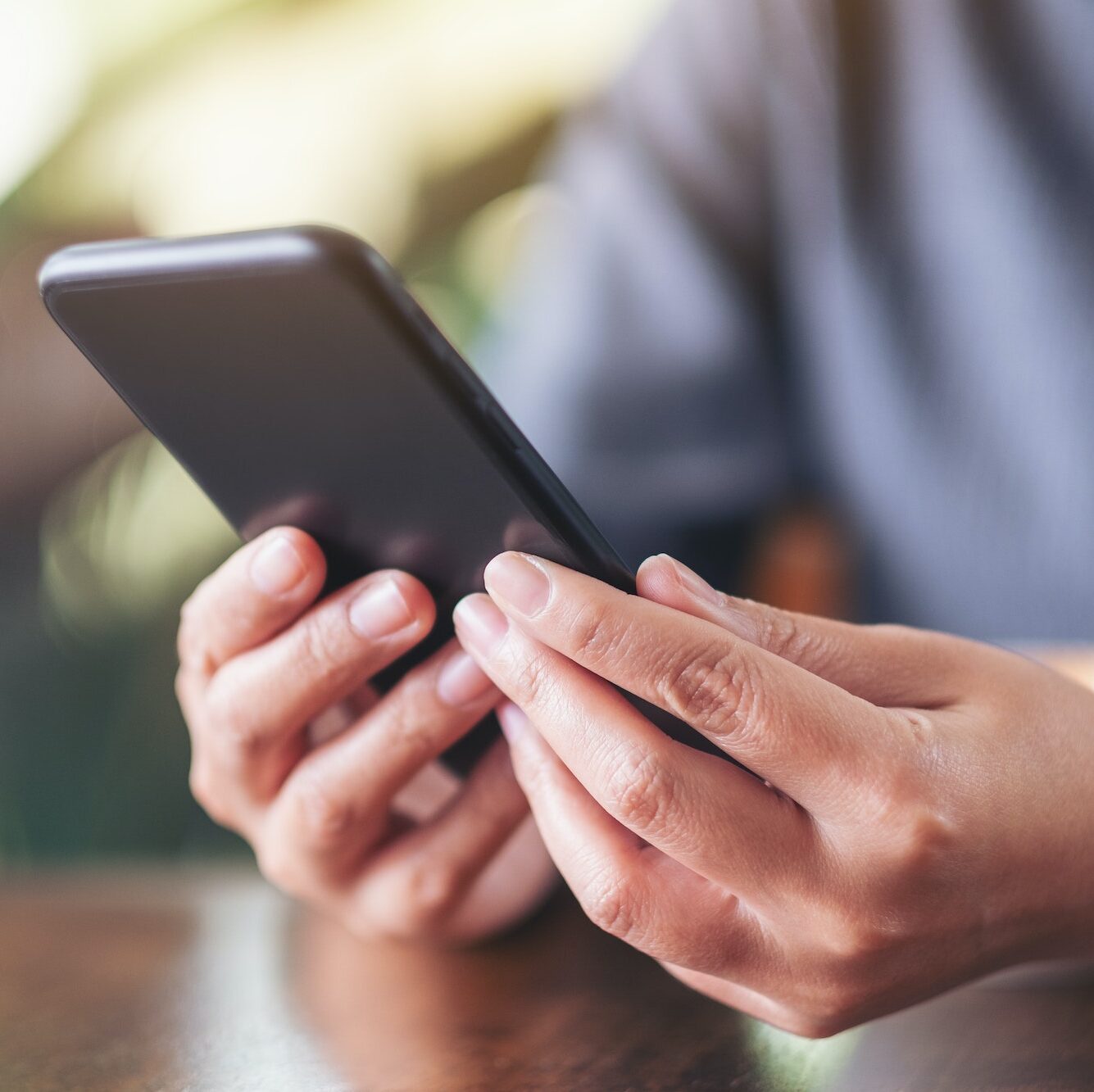 Closeup image of a woman holding , using and looking at smart phone