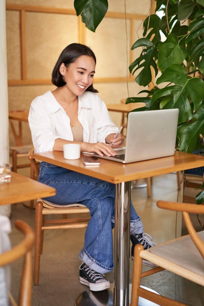 Stylish businesswoman with laptop, sitting in cafe and working on computer, managing business and